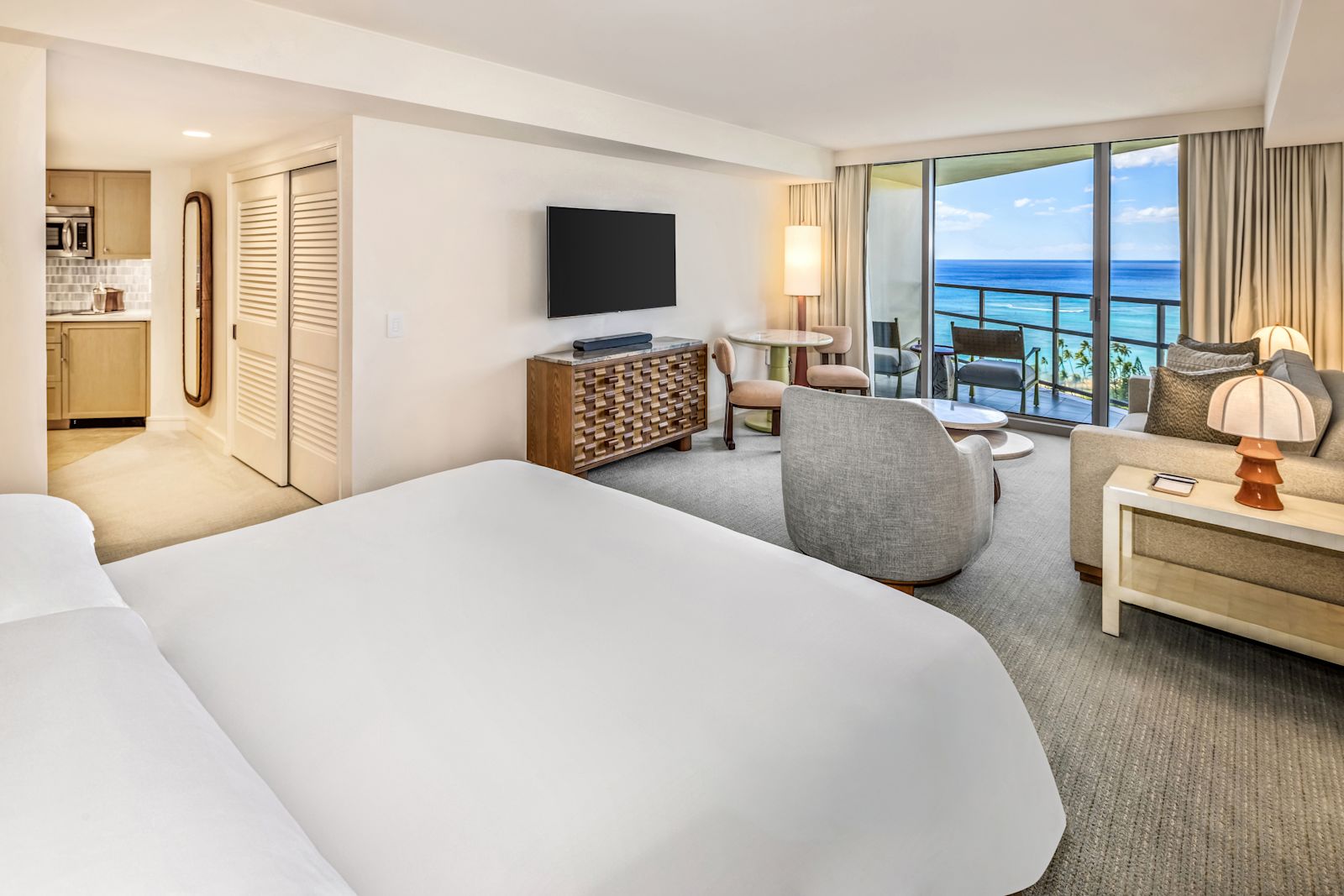 A guest room with a bed, a sofa and an ocean-view balcony at Ka La'i Waikiki Beach