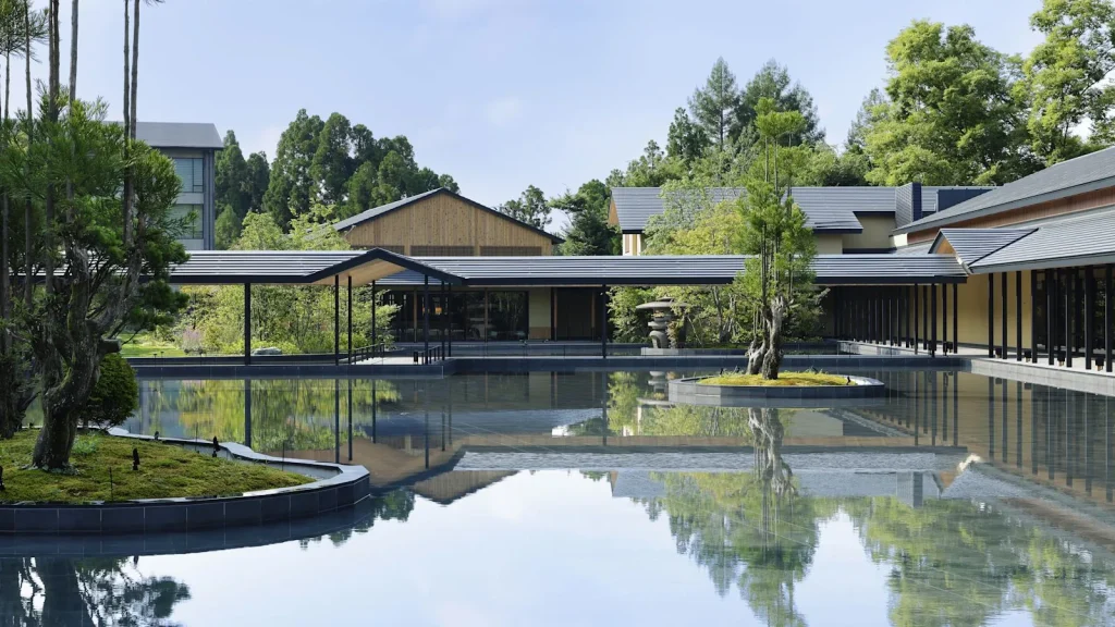 ROKU Kyoto's low buildings around a reflecting pool with a tree on a small island